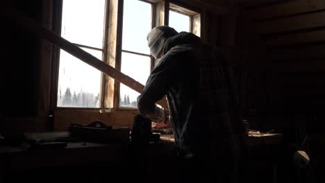 Person-is-working-on-old-and-dusty-wood-workbench-against-window-light