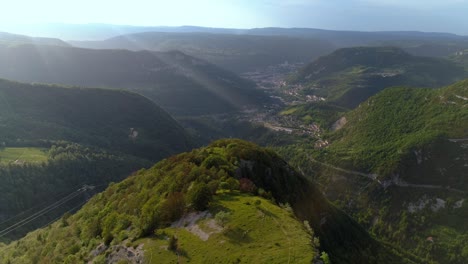 Aerial-view-of-green-french-Jura-mountains-with-sun-flare-and-Saint-Claude-city-in-the-valley-background
