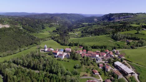 Aerial-flyover-french-village-Les-Bouchoux-during-sunny-day-and-green-landscape