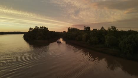 Aerial-drone-shot-of-ship-carrying-small-boat-on-Amazon-River-during-beautiful-sunset