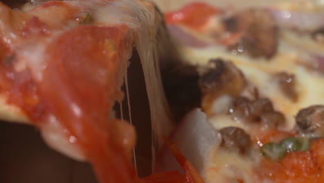 Picking-up-a-slice-of-fresh-pizza-with-the-melted-cheese-stretching-as-the-pieces-separate---close-up-isolated