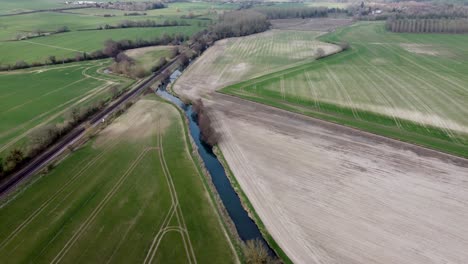 Aerial-view-of-a-river-and-a-railway-line-with-green-fields