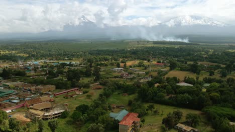 Aerial-view-over-a-town-towards-burning-fields-of-rural-sunny-Africa---drone-shot