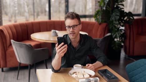 Süßer-Junger-Blogger-In-Einem-Café-Dreht-Ein-Video-Auf-Einem-Smartphone
