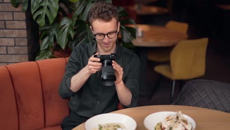Handsome-young-man-takes-pictures-of-dishes-in-a-cafe