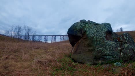 A-cloudy-time-lapse-in-the-Appalachian-grasslands-with-a-viaduct-in-the-background-and-a-boulder-in-the-foreground