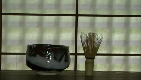 Japanische-Teeschale-Auf-Regal-Vor-Fenster-Aus-Maulbeerpapier