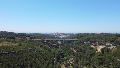 AERIAL-A-Tall-Bridge-With-Traffic-with-the-city-of-Cascais-in-the-Background,-Portugal