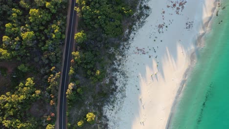Eine-Leere-Küstenstraße-Und-Ein-Tropischer-Weißer-Sandstrand,-Drohnen-Luftbild-Von-Oben-Nach-Unten