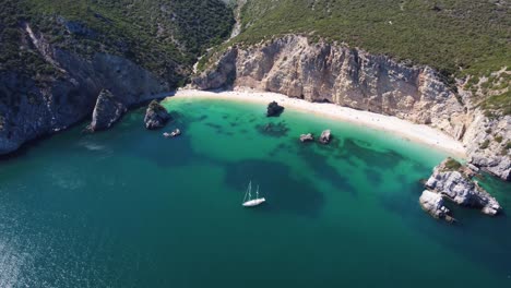 Aufsteigende,-Wegfliegende-Luftaufnahme-Einer-Yacht,-Die-An-Einem-Tropisch-Aussehenden-Strand-In-Portugal-Festmacht