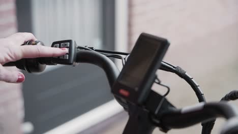 Frau-Schaltet-Ihr-E-Bike-Mit-Den-Bedienelementen-Am-Lenker-Ein-Und-Das-Display-Leuchtet-Auf