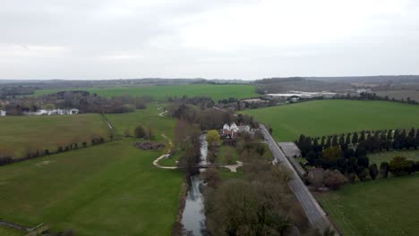 Aerial-view-of-a-river-and-houses-next-to-a-road-and-fields
