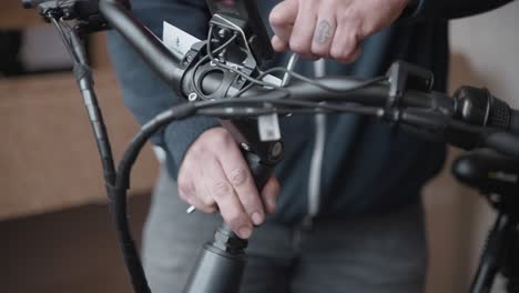 Man-uses-a-allan-key-to-set-the-height-of-the-handles-bars-of-a-electric-bike-after-adjusting-the-height-of-the-steering-shaft