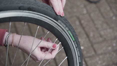 Lady-adjusts-the-air-pressure-in-her-electric-bike-tires-and-installs-the-valve-cap-on-the-bike-tire-outside