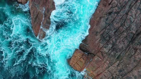High-angle-aerial-view-of-ocean-waves-breaking-on-scenic-eroded-rock-formations