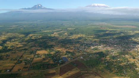 Aerial-view-cloud-shadows-moving-over-fields-on-the-countryside-of-Kenya,-Kilimanjaro-mountain-background---tracking,-drone-shot