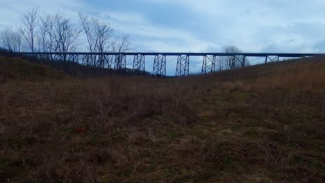 A-cloudy-time-lapse-in-the-Appalachian-grasslands-with-a-train-passing-on-a-viaduct-in-the-background-and-a-boulder-in-the-foreground