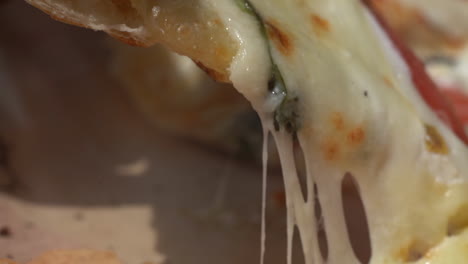 Ein-Stück-Frischer-Leckerer-Pizza-Aufheben,-Bei-Dem-Sich-Der-Käse-Beim-Auseinanderziehen-Dehnt---Nahaufnahme