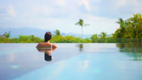 Back-view-of-woman-in-infinity-pool-looking-at-panorama