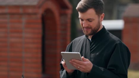 Cute-male-monk-in-a-black-robe-on-the-street-with-a-laptop