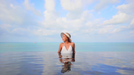 Asian-skinny-woman-enjoying-the-sea-view-from-the-inside-infinity-pool-front-view-daytime-cloudscape