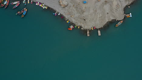 Aerial-top-view-over-Attabad-lake-shore-with-colorful-boats-and-houses