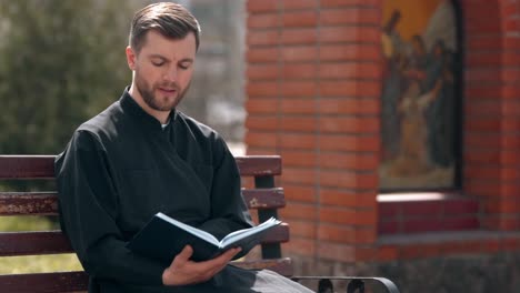 Ein-Hübscher-Priester-Liest-Ein-Gebetbuch-Und-Lächelt-Glücklich