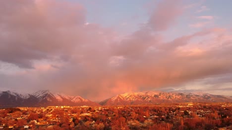 Drone-shot-at-sunset-golden-hour-of-Northern-Utah-mountains-as-sun-is-beaming-onto-them,-with-beautiful-clouds-and-cotton-candy-sky