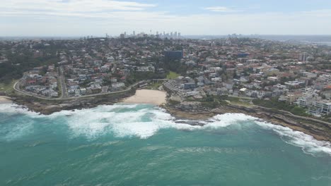 Cityscape-In-Tamarama-Beach-With-Splashing-Waves-From-Mackenzies-Bay---Eastern-Suburbs,-Sydney,-New-South-Wales,-Australia