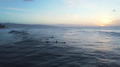 Surfers-waiting-for-big-sea-wave-at-sunset,-North-coast-Oahu-island,-Hawaii