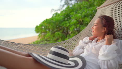 Beautiful-Woman-Relaxing-in-Swinging-Hammock-on-Tropical-Beach-SLOMO