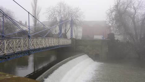 Puente-Peatonal-De-Hierro-Victoriano-Ornamentado-Sobre-Una-Represa-En-El-Río-Leam-En-Un-Día-Frío-Y-Brumoso-En-Leamington-Spa,-Warwickshire,-Inglaterra