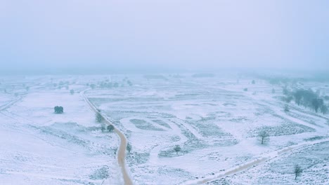 Winter-Landscape-Of-Vast-Terrain-Countryside-With-Scenic-Empty-Road-On-A-Gloomy-Snowstorm