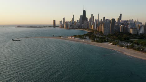 High-Aerial-View-of-Lake-Michigan-Beaches-with-Chicago-Skyline-in-Background-during-Golden-Hour
