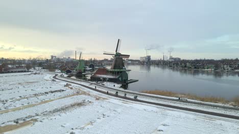 Group-of-tourist-cycling-alongside-iconic-windmills-at-Zaanse-Schans-during-winter