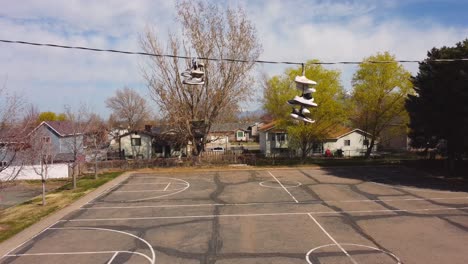 Slow-pan-down-from-shoes-trainers-on-wrapped-around-telephone-phone-wire-down-to-small-and-empty-distressed-basketball-court-after-covid-19-lockdowns-end