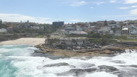 Dangerous-Waves-Over-Rocky-Shore-With-Surfers-At-Tamarama-Point-Headland-In-Eastern-Suburbs,-Sydney,-New-South-Wales,-Australia