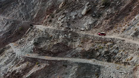Jeep-Rojo-Conduciendo-Por-Una-Carretera-De-Montaña-Mortal-Hacia-Los-Prados-De-Hadas,-Pakistán