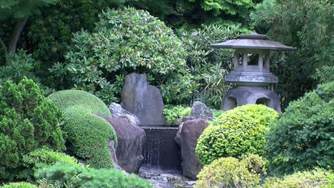 A-stone-lantern-stands-next-to-a-waterfall-in-a-Japanese-garden
