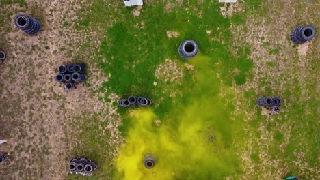 Smoke-flare-activated-on-a-paintball-battle-field-with-players-playing-a-match-drone-shot