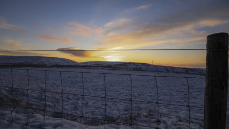 Timelapse-of-a-snowy-field-with-a-sunset-and-a-open-link-sheep-fence