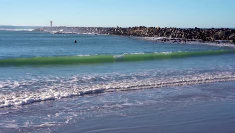 Surfer-Im-Meer-Mit-Extremen-Wellen,-Die-Auf-Felsige-Breakwall-Krachen