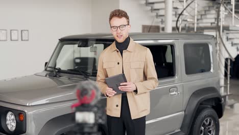 handsome-young-man-in-a-car-dealership-talks-about-the-car-filming-everything-on-video