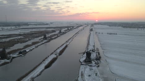 High-above-Kinderdijk-windmills-with-snow-covered-land-at-early-sunrise