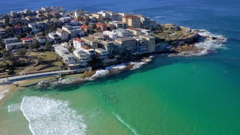 Aerial-View-Of-Hotel-Buildings-In-Ben-Buckler-Point-With-Surfers-Swimming-In-Blue-Sea