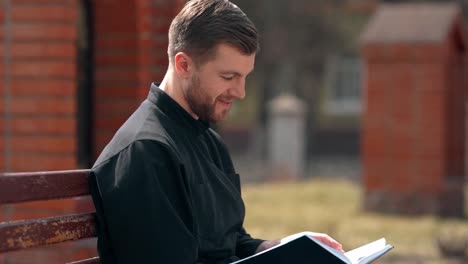 closeup-portrait-of-a-reading-priest-sitting-on-a-bench