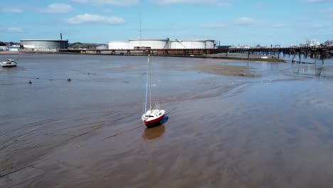 Small-red-fishing-boat-aerial-view-of-stranded-vessel-on-muddy-low-tide-on-Liverpool-coastline