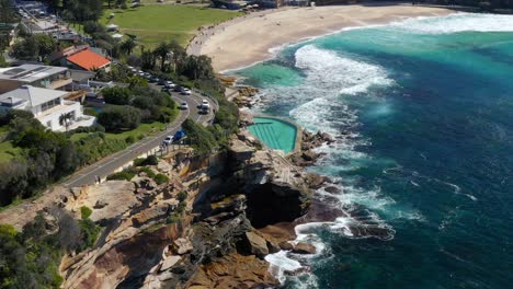 Drohne-In-Richtung-Bronte-Ocean-Pool-Mit-Wellen,-Die-In-Bronte-Beach,-New-South-Wales,-Australien,-In-Die-Felsige-Küste-Stürzen