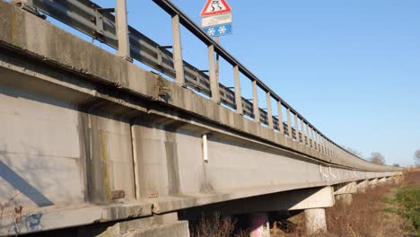 Lange-Brücke,-Die-Von-Großen-Stahlbetonpfeilern-Getragen-Wird,-Von-Der-Seite-Gesehen,-Mit-Vegetation-Darunter
