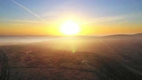 Spektakulärer-Goldener-Sonnenuntergang---Drohne-Fliegt-Hoch-über-Gleitschirm,-England